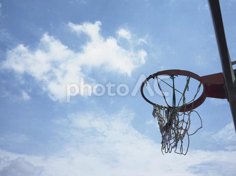 網が破れたバスケットボールリングと青空