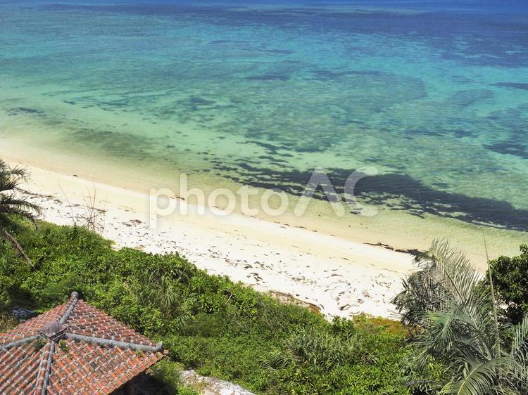 サンゴ礁の海とビーチ、ヤシの木と赤瓦屋根