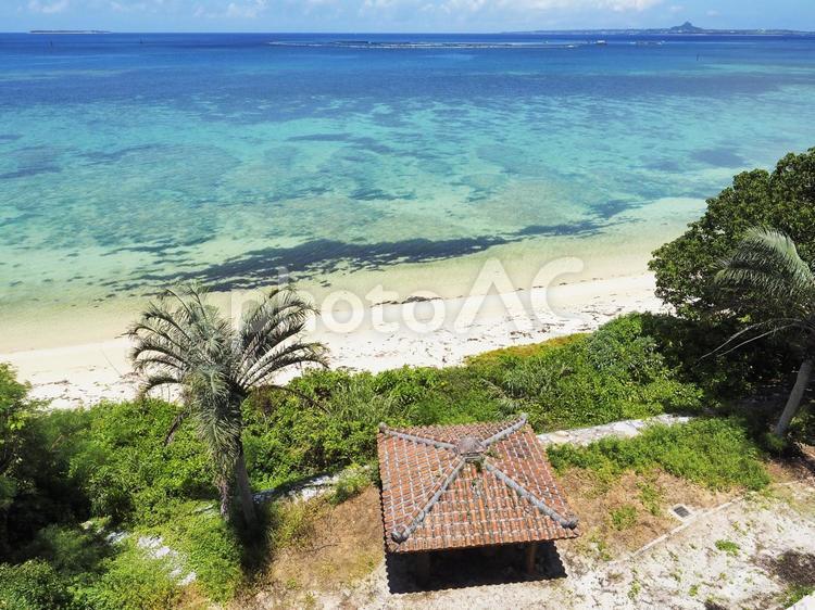 サンゴ礁の海とビーチ、ヤシの木と赤瓦屋根